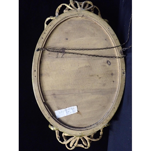 745 - A GILTWOOD WALL MIRROR

the bevelled oval plate with within reeded border with ribbon tie cresting 7... 