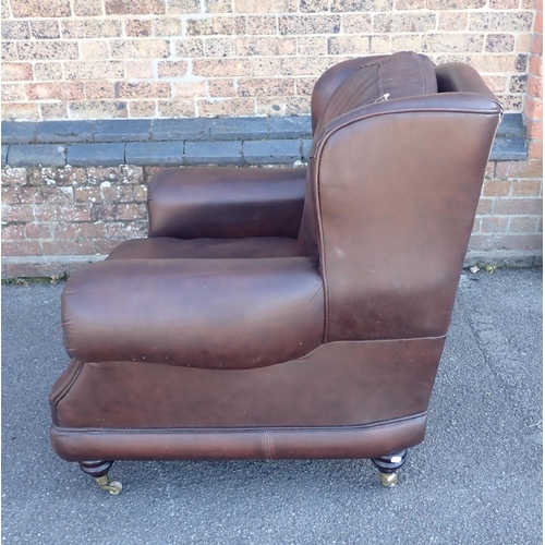 830 - A THOMAS LLOYD BROWN LEATHER CLUB STYLE WING ARMCHAIR

on turned feet with brass castors 97cm wide (... 