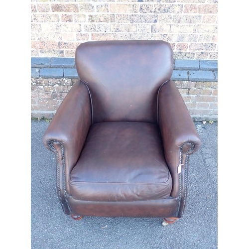 831 - A THOMAS LLOYD STUDDED BROWN LEATHER CLUB STYLE ARMCHAIR

with turned front legs and brass castors 8... 