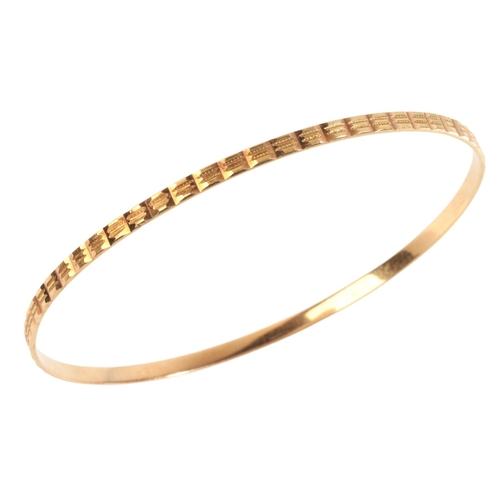 256 - A GOLD BANGLE

in 9ct gold, with engine-turned design, indistinct assay marks, internal circumferenc... 