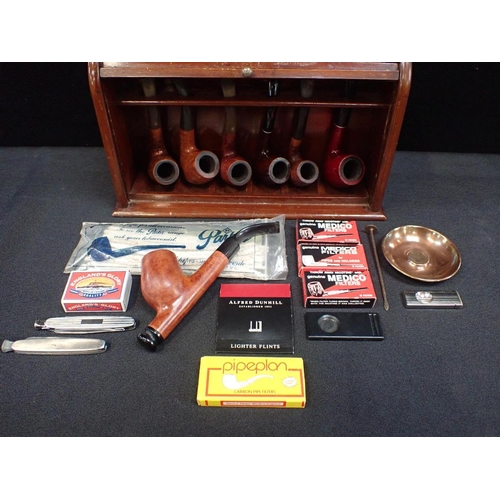 181 - A MAHOGANY PIPE RACK WITH TAMBOUR FRONT

with a collection of vintage pipes and smoking accessories