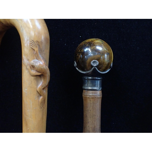 87 - A SILVER-MOUNTED WALKING CANE WITH TIGER'S EYE KNOB

a silver-topped cane, a carved walking stick, a... 