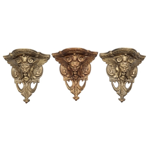 321 - A SET OF THREE GILDED WALL BRACKETS

20th century, each figured with winged masks, 30cm high x 30cm ... 