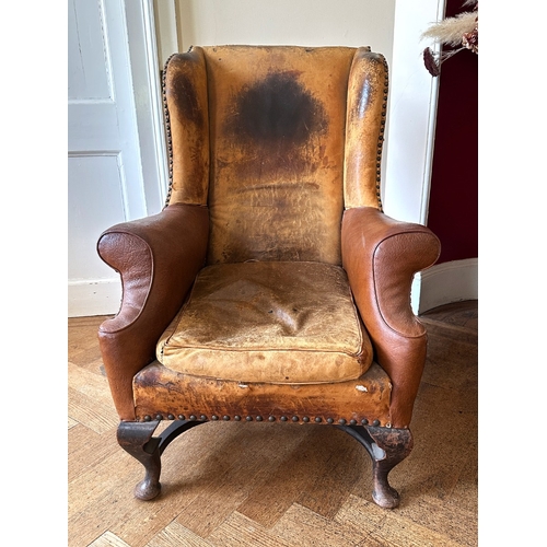 25 - A MAHOGANY WINGBACK ARMCHAIR

stamped '34544' to a back leg, with distressed leather covers, on shor... 