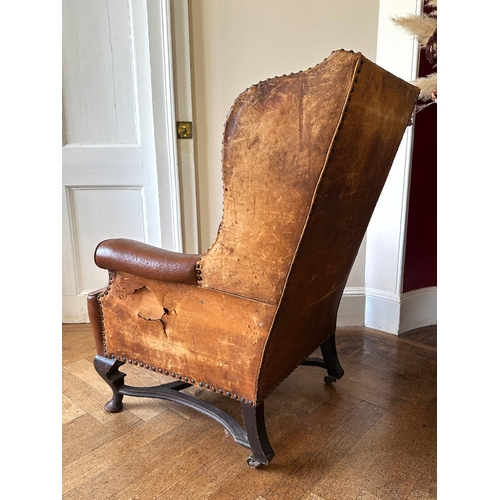 25 - A MAHOGANY WINGBACK ARMCHAIR

stamped '34544' to a back leg, with distressed leather covers, on shor... 