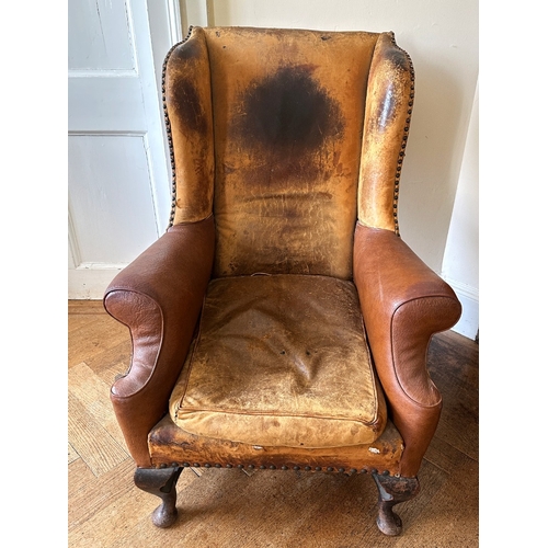 25 - A MAHOGANY WINGBACK ARMCHAIR

stamped '34544' to a back leg, with distressed leather covers, on shor... 