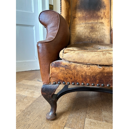 25 - A MAHOGANY WINGBACK ARMCHAIR

stamped '34544' to a back leg, with distressed leather covers, on shor... 