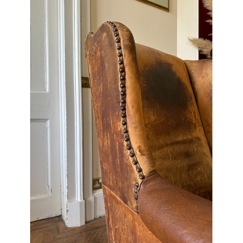 25 - A MAHOGANY WINGBACK ARMCHAIR

stamped '34544' to a back leg, with distressed leather covers, on shor... 