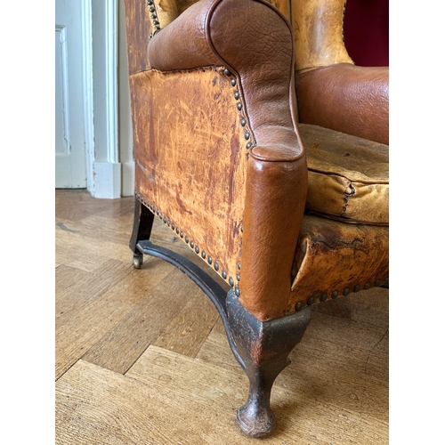 25 - A MAHOGANY WINGBACK ARMCHAIR

stamped '34544' to a back leg, with distressed leather covers, on shor... 