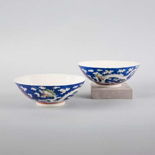 117 - A PAIR OF CHINESE PORCELAIN 'DRAGON' BOWLS

20th century, the blue grounds decorated in white enamel... 