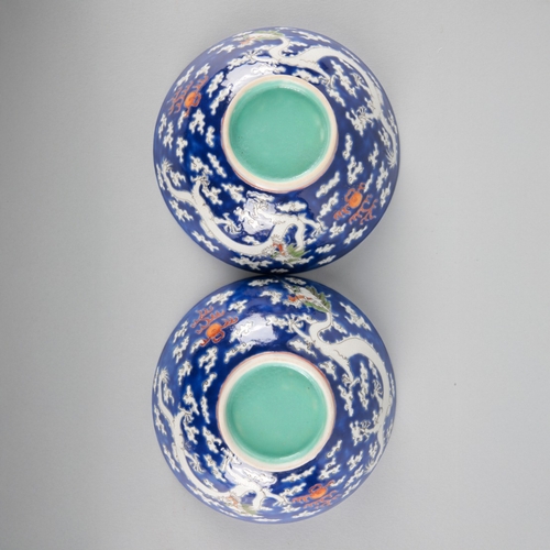 117 - A PAIR OF CHINESE PORCELAIN 'DRAGON' BOWLS

20th century, the blue grounds decorated in white enamel... 