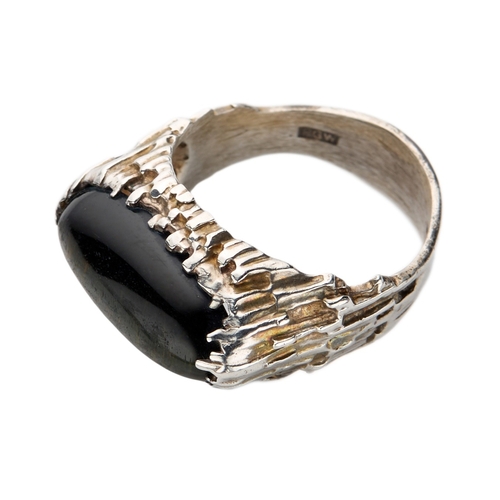 180 - PETER GUY WATSON; A MODERNIST SILVER AND BLACK DYED TIGER EYE RING the oval black tiger eye cabochon... 
