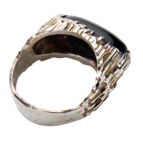 180 - PETER GUY WATSON; A MODERNIST SILVER AND BLACK DYED TIGER EYE RING the oval black tiger eye cabochon... 