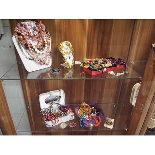 67 - Four shelves full of costume jewellery including beads, brooches, bangles, earrings etc.