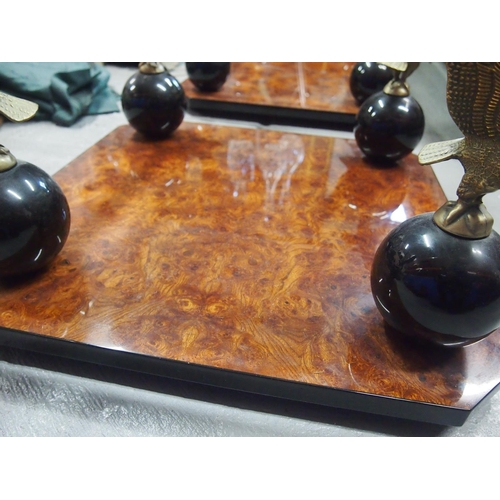 87 - A bevelled glass top square table with burr walnut design to base with Eagle perched on ball pedesta... 