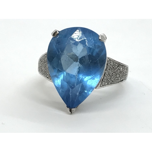 127 - A white gold blue topaz pear shaped ring with diamonds to the mount, unmarked, approx. size M