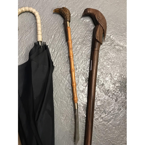 35 - A shoehorn and walking stick with eagle/bird's head to handles plus three vintage umbrellas, one wit... 