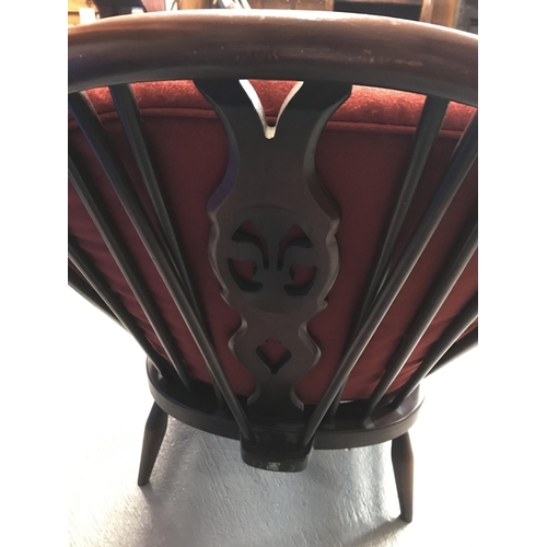 98 - An Ercol fireside chair with spindle and Fleur de Lys detailing with red fabric cushion