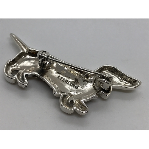 211 - A silver dachshund brooch, set with rubies stamped sterling