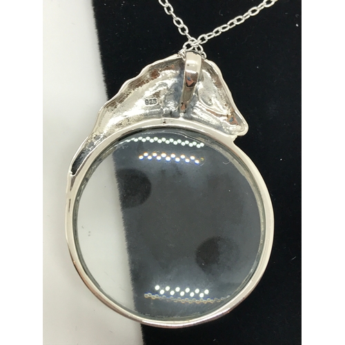 216 - A silver magnifying glass pendant in the form of a horse stamped 925 with silver chain