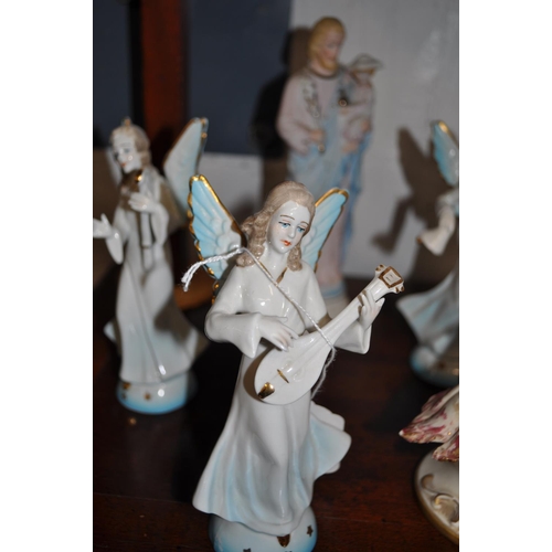 4 - German ceramic angelic figurines together with a period boy cherub holding a swan - a/f