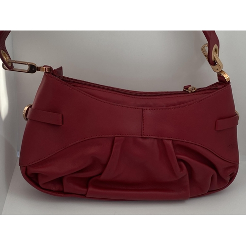 17 - A genuine Coccinelle leather handbag  featuring a striking red soft leather with contrasting gold to... 