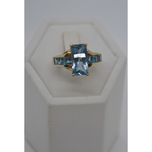 120 - 9ct yellow gold ring with faceted rectangular blue stone - possibly topaz, with co-ordinating square... 