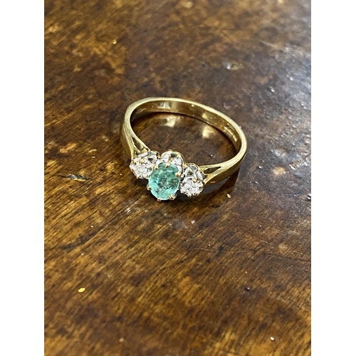 103 - A 9ct yellow gold ring with oval green central stone and a diamond either side of shank, approx size... 