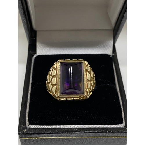 95 - A 9ct yellow ring, hallmarked London  with polished purple raised stone, with a patterned design to ... 