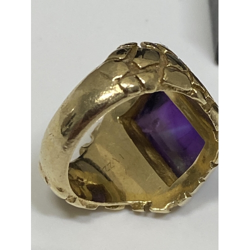 95 - A 9ct yellow ring, hallmarked London  with polished purple raised stone, with a patterned design to ... 