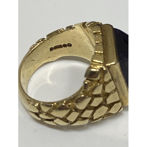 95 - A 9ct yellow ring, hallmarked London  with polished purple raised stone, with a patterned design to ... 