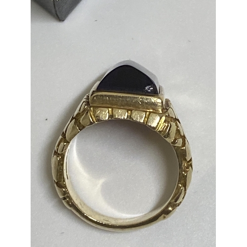 95 - A 9ct yellow ring, hallmarked London  with polished purple raised stone, with a patterned design to ... 