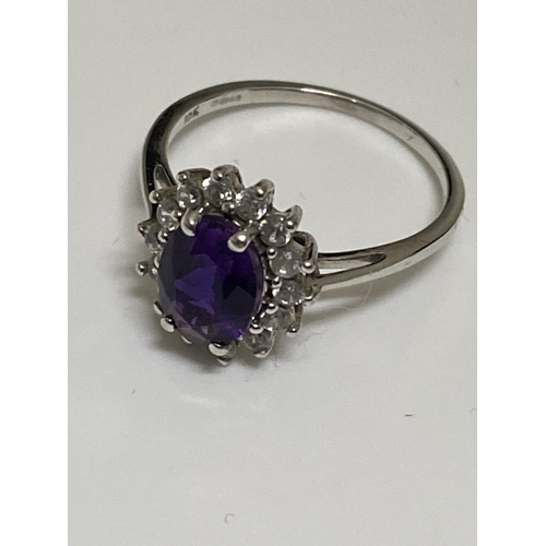 129 - A ladies cluster ring, marked 10ct. Central oval purple stone surrounding clear stones, hallmarked 3... 