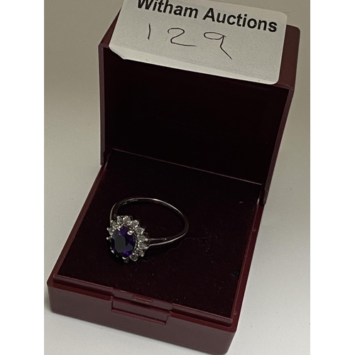 129 - A ladies cluster ring, marked 10ct. Central oval purple stone surrounding clear stones, hallmarked 3... 