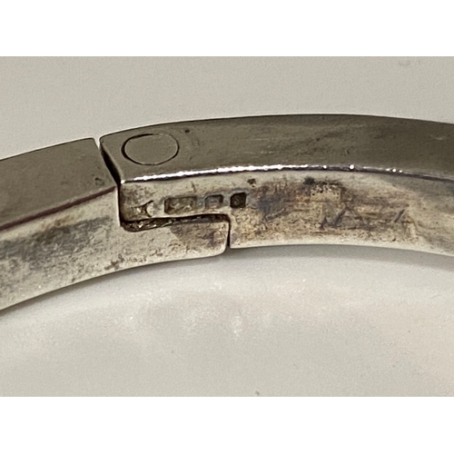 68 - A silver bangle hallmarked London silver with raised relief design of musical notes tested as 9ct ye... 