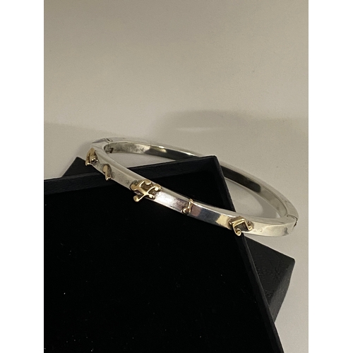 68 - A silver bangle hallmarked London silver with raised relief design of musical notes tested as 9ct ye... 