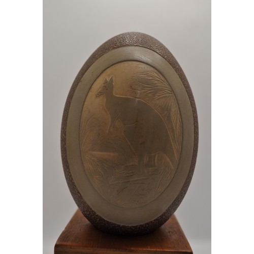 49 - Emu egg with carved kangaroo scene, with a wooden stand