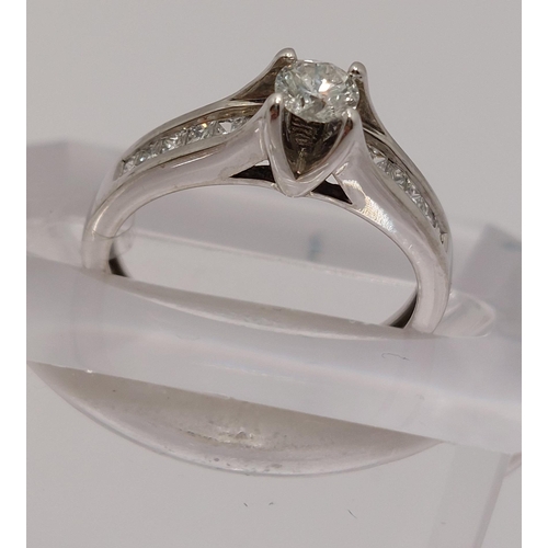 78 - 18ct white gold diamond ring, central round cut stone of approx 0.20ct, with additional x12 princess... 