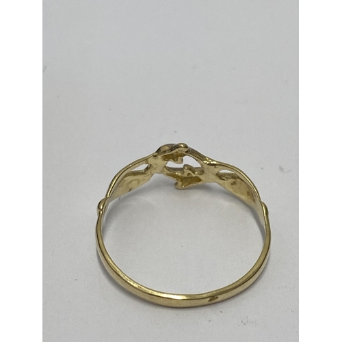 217 - A yellow gold ring with design depicting two hands holding a pair of dolphins, stamped 18kt (tested)... 