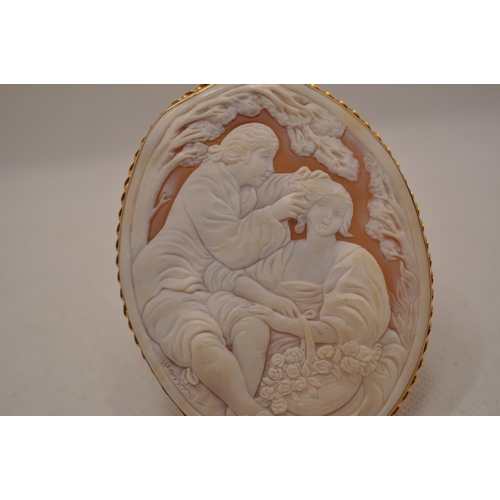 113 - A large 15ct yellow gold cameo pendant / brooch, depicting romantic scene of man placing flower in h... 