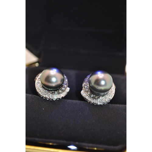 147 - A pair of white gold stud earrings with central pearl with surrounding diamonds, stamped 585