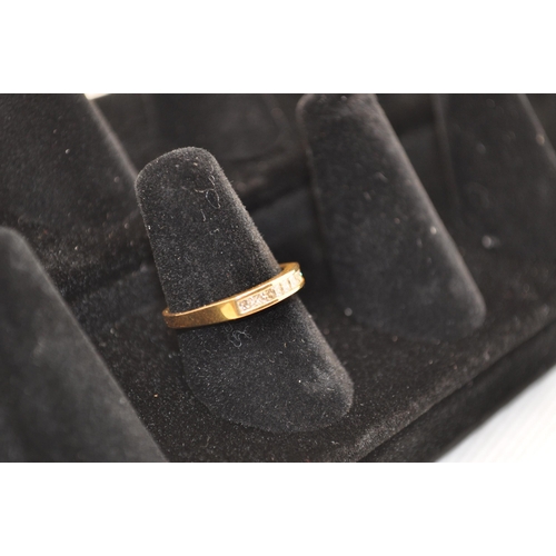 189 - An 18ct gold ring with a row insert channel of 9 princess cut diamonds Approx. size M