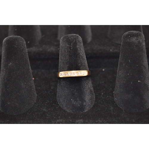 189 - An 18ct gold ring with a row insert channel of 9 princess cut diamonds Approx. size M