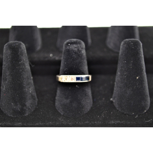 229 - A diamond and sapphire gold ring . The ring being channel set with three square cut sapphires and th... 