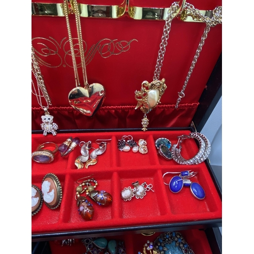 132 - A jewellery box containing a large quantity of costume jewellery to include lockets, snake rings, br... 