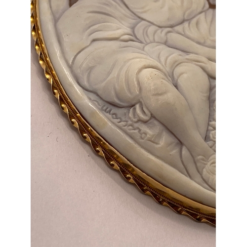 113 - A large 15ct yellow gold cameo pendant / brooch, depicting romantic scene of man placing flower in h... 