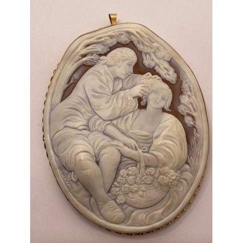 113 - A large 15ct yellow gold cameo pendant / brooch, depicting romantic scene of man placing flower in h... 