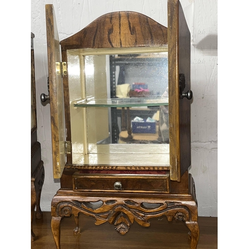 129 - A  miniature display cabinet constructed in walnut with shell handles detailing, mirrored back and g... 