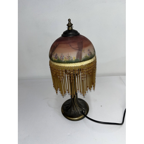 65 - A table lamp with glass shade decorated with a dragonfly garden and tassels. Working at time of cata... 