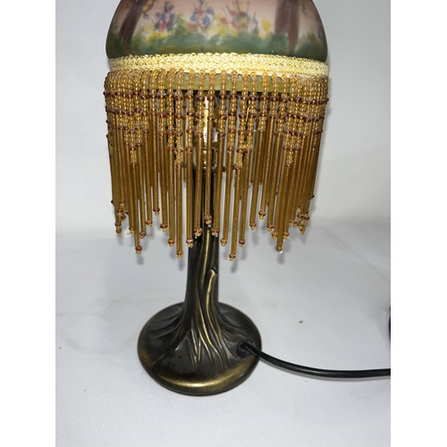 65 - A table lamp with glass shade decorated with a dragonfly garden and tassels. Working at time of cata... 